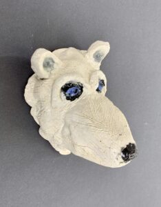 a sculpted clay polar bear head painted white with blue eyes