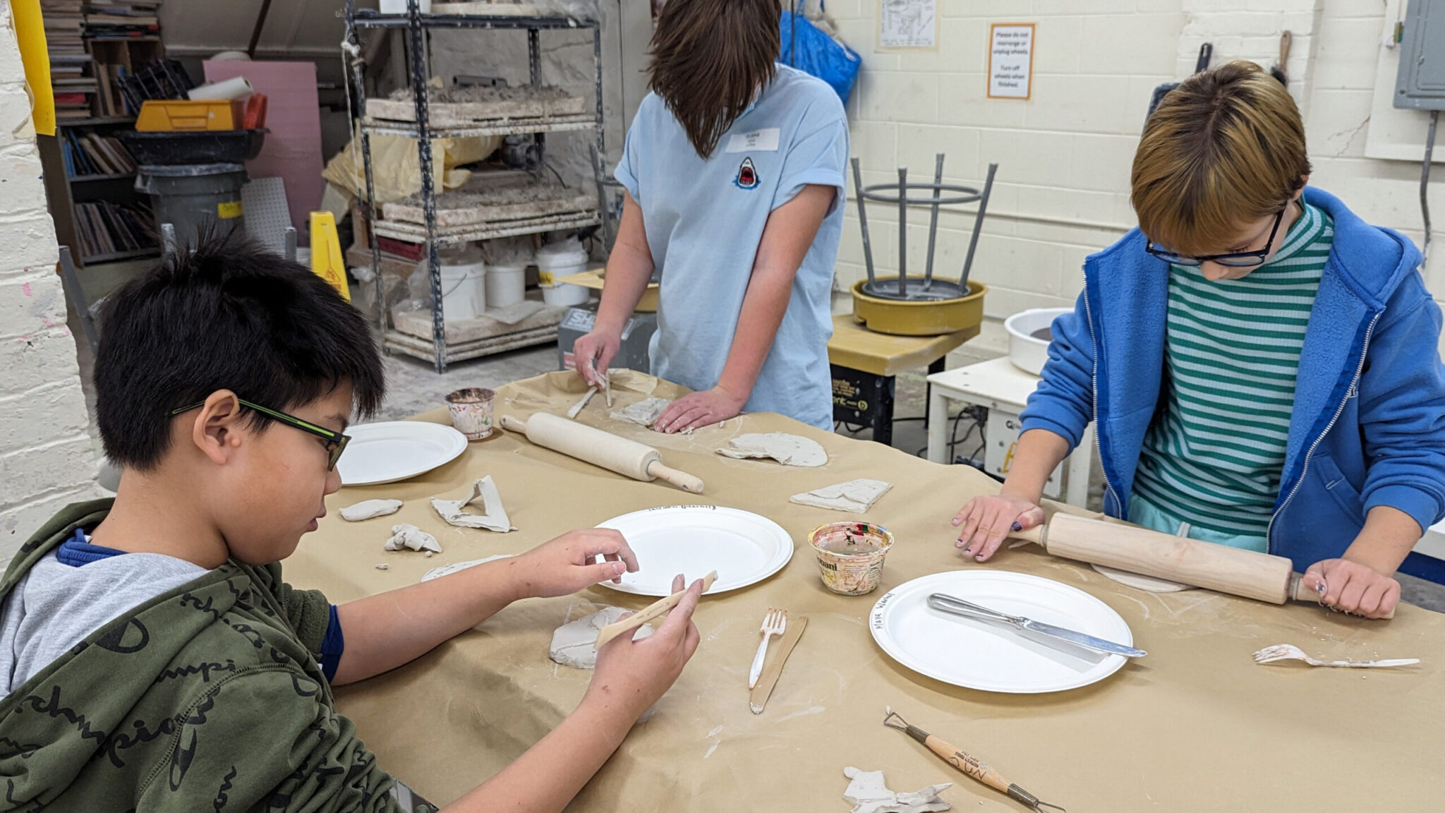 Students roll and shape clay