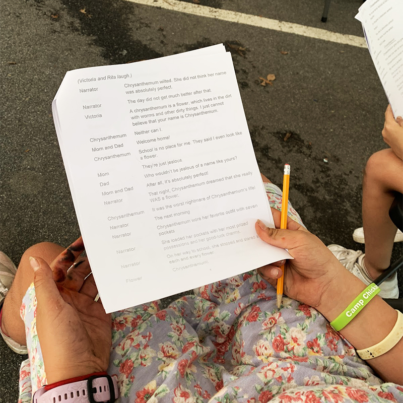 A camper holds a script in their hand with a pencil