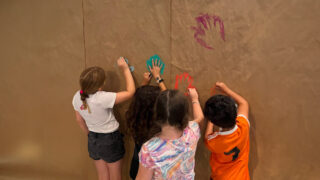 Children joyfully creating colorful chalk drawings on a wall, showcasing their creativity and imagination in a playful setting.